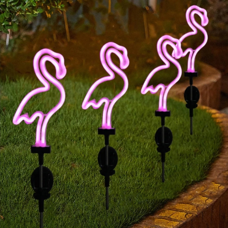 Four pink flamingo-shaped garden lights on grass