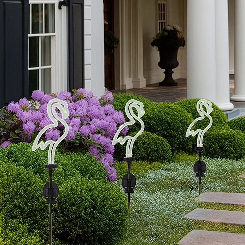 Neon flamingo lights in a garden setting with a house in the background