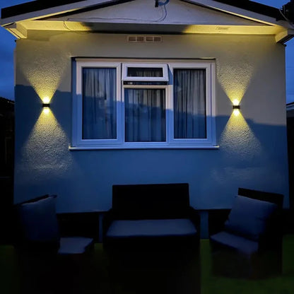 Outdoor seating area in front of a house with wall lights on