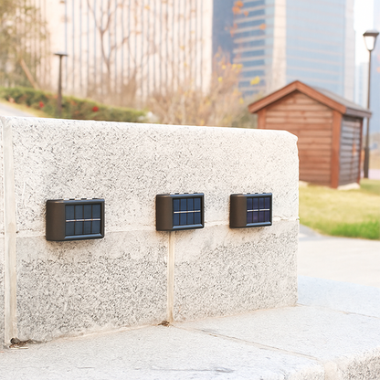 Three solar panels attached to a concrete wall outdoors with a blurred background
