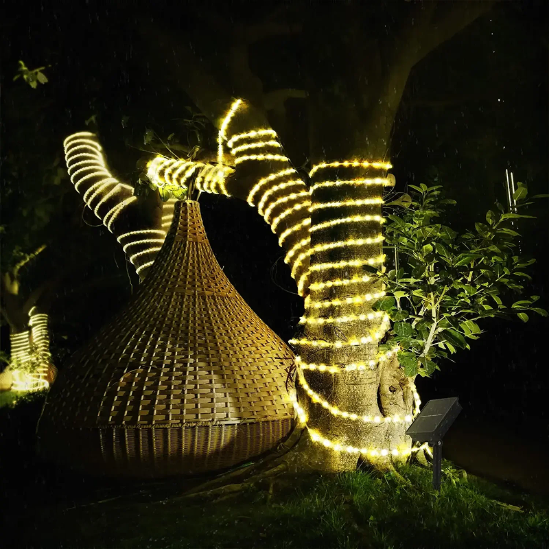 Decorative outdoor light installation shaped like a bow with a woven basket underneath, set against a dark background.