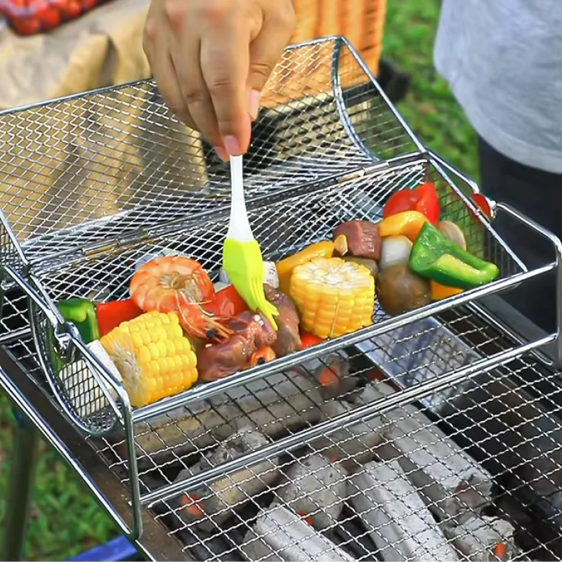 Metal mesh grill basket with vegetables being used on a grill outdoors