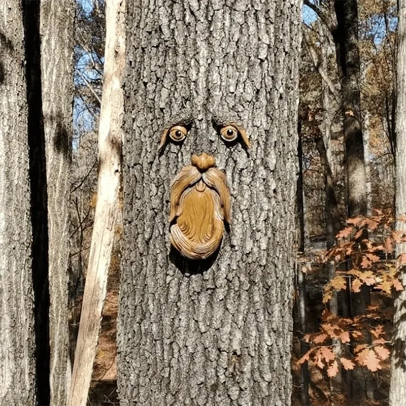 Wooden face sculpture carved into a tree trunk in a forest setting