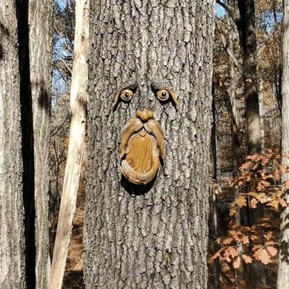 Wooden face sculpture carved into a tree trunk in a forest setting