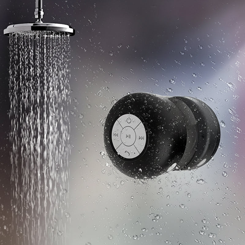 Shower head with water droplets and a black Bluetooth speaker in the shower