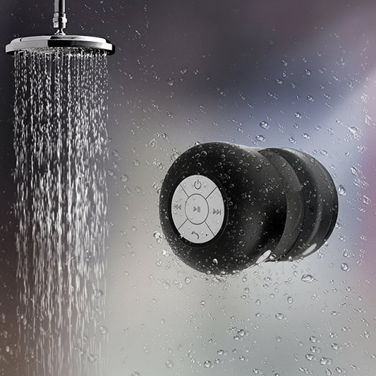 Shower head with water droplets and a black Bluetooth speaker in the shower