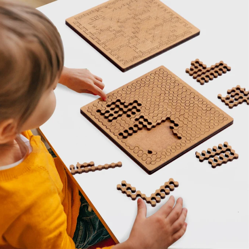 Child playing with wooden puzzle pieces on a white surface