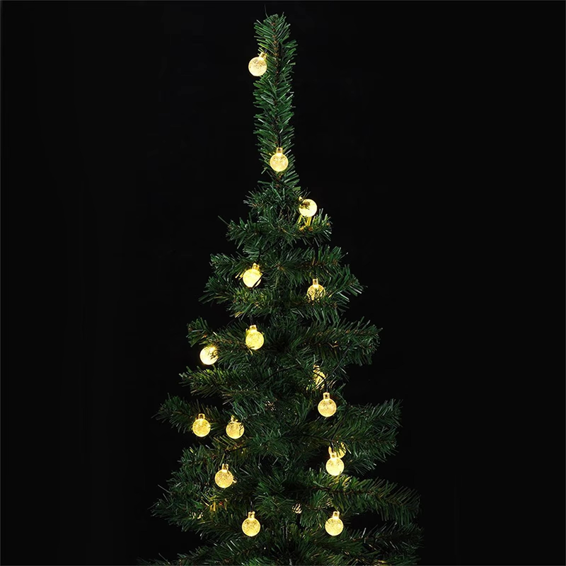Small artificial Christmas tree with string lights on a black background